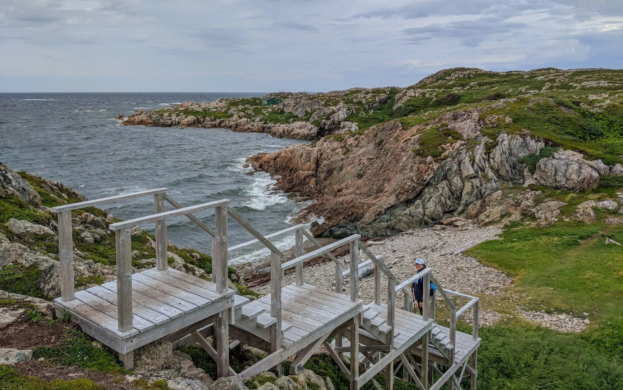 Wooden steps going down to a pebble cove between pink granite headlands at Joe Batt's Arm.