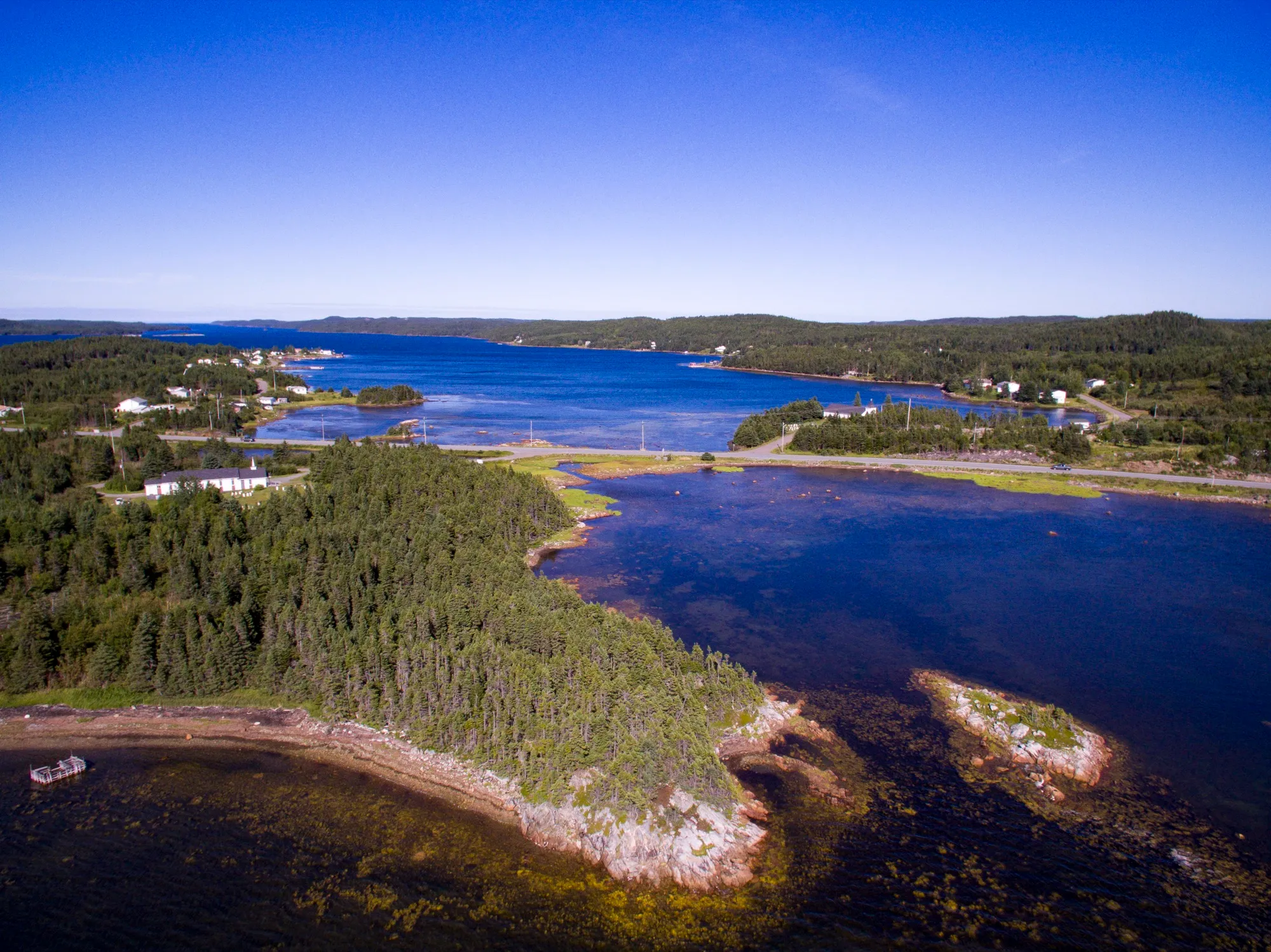 Aerial over Boyd's Cove harbour and islands, deep blue.