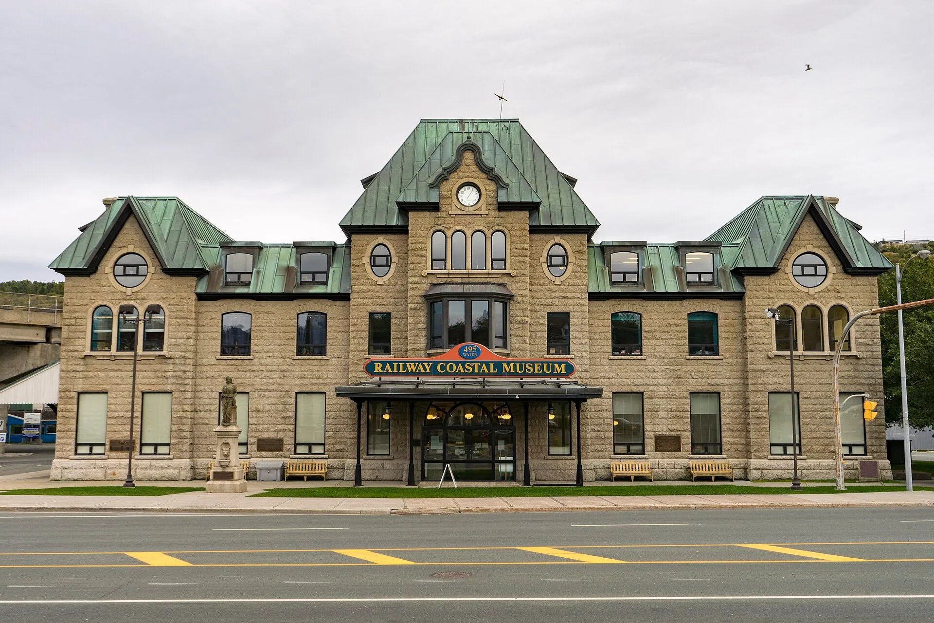 The stone former railway station in St. John's with green copper roofs and a Railway Coastal Museum sign over the entrance.