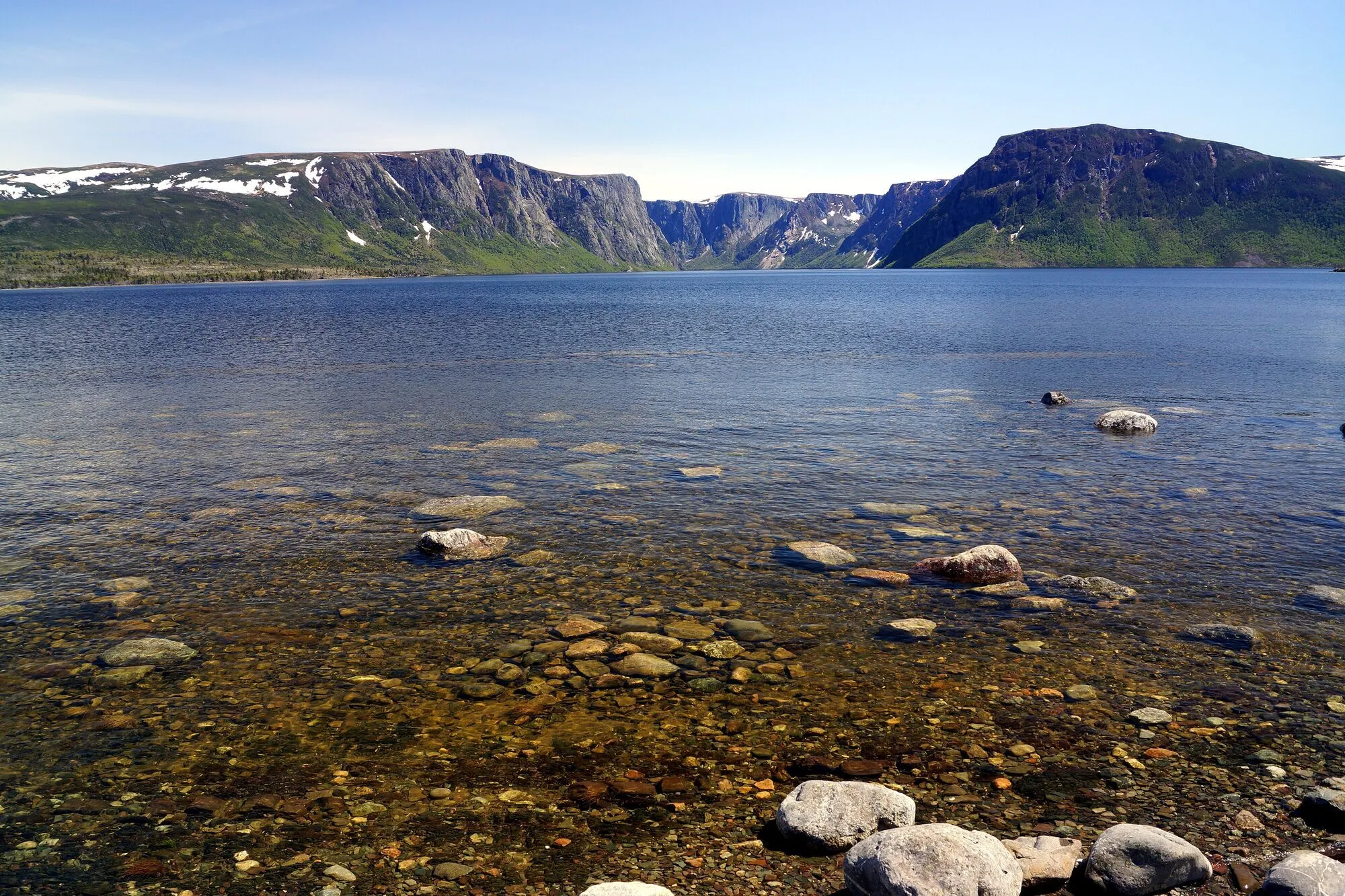 Western Brook Pond from its stony shore near the outlet, the gorge cliffs at the far end.