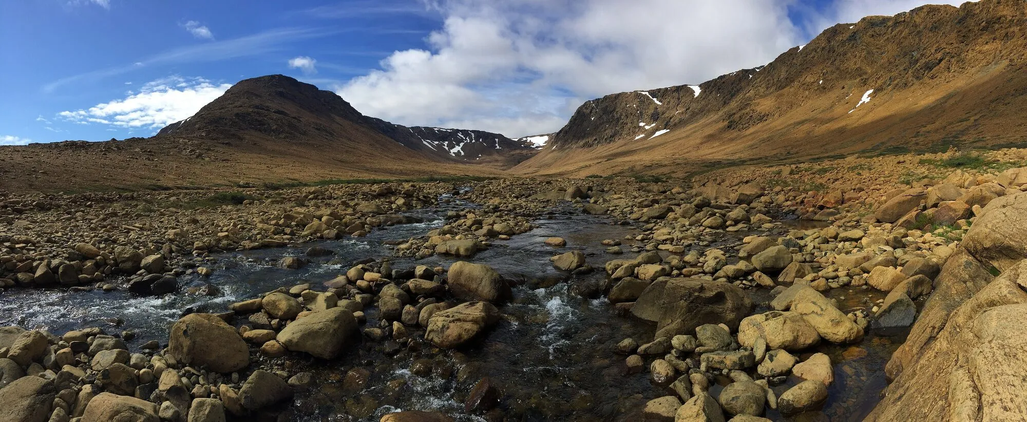 A stony brook running between the bare orange-brown hills of the Tablelands.